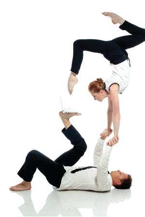 acrobats balancing and reaching with foot toward computer